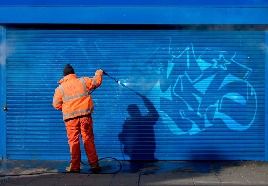 Washing graffiti off a security grill.